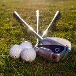 Guides & Tips 9 Golf clubs and balls arranged on a sunlit grass field, perfect sports imagery.