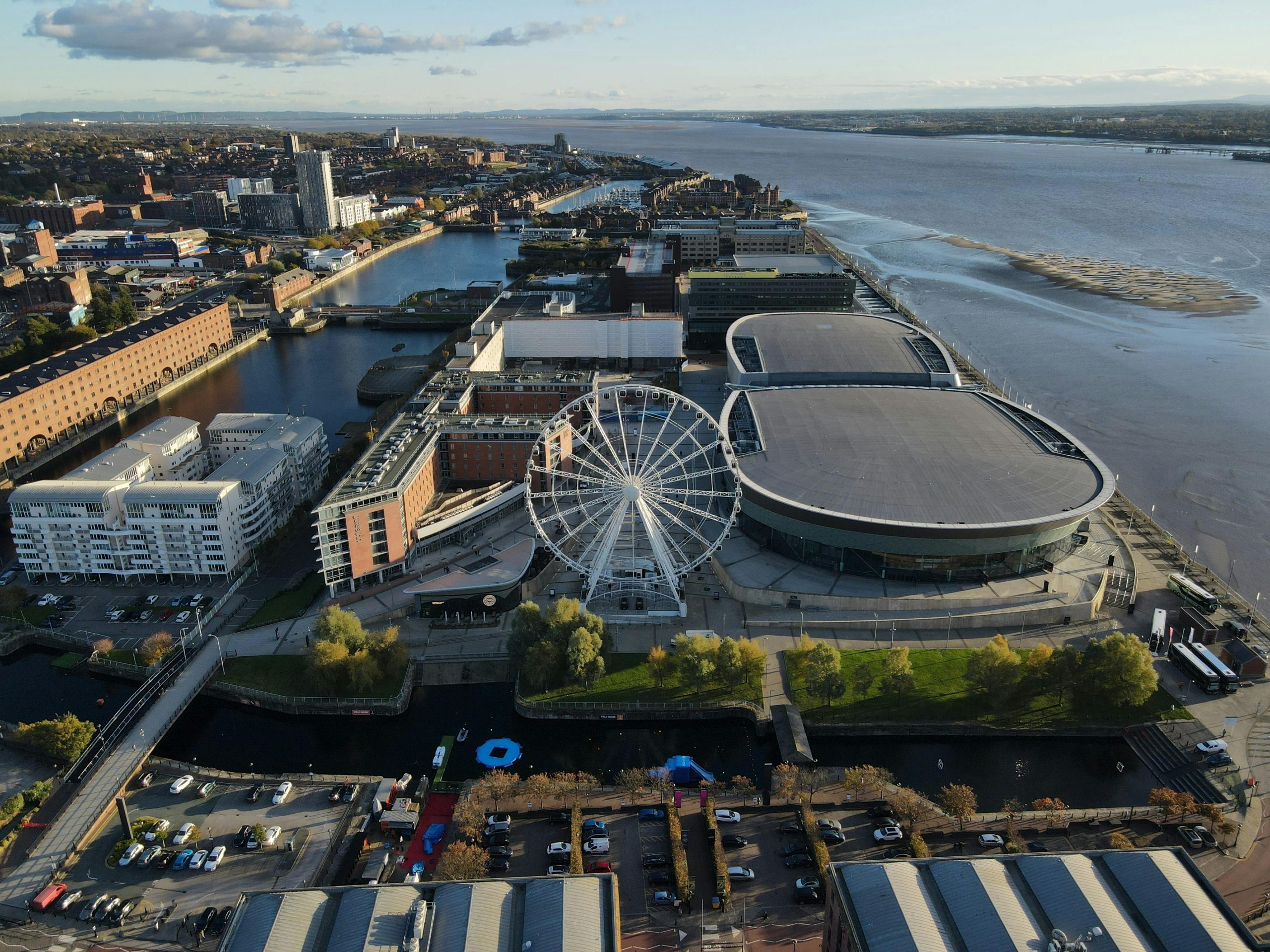 A stunning aerial view of Liverpool's waterfront featuring a prominent ferris wheel and modern cityscape.