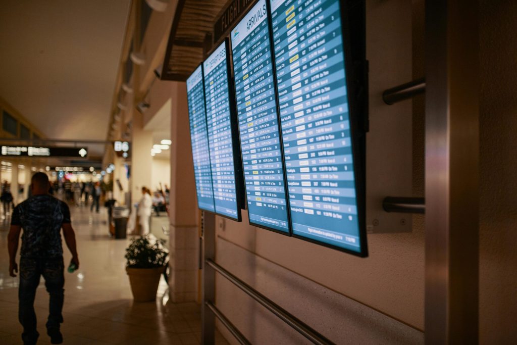 Airport Transfers 8 Airport terminal with digital flight information boards showing arrivals and departures.