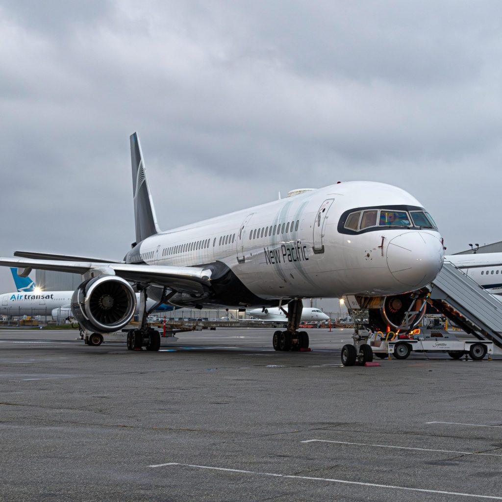 Commercial airplane parked at an airport during the day with cloudy skies.