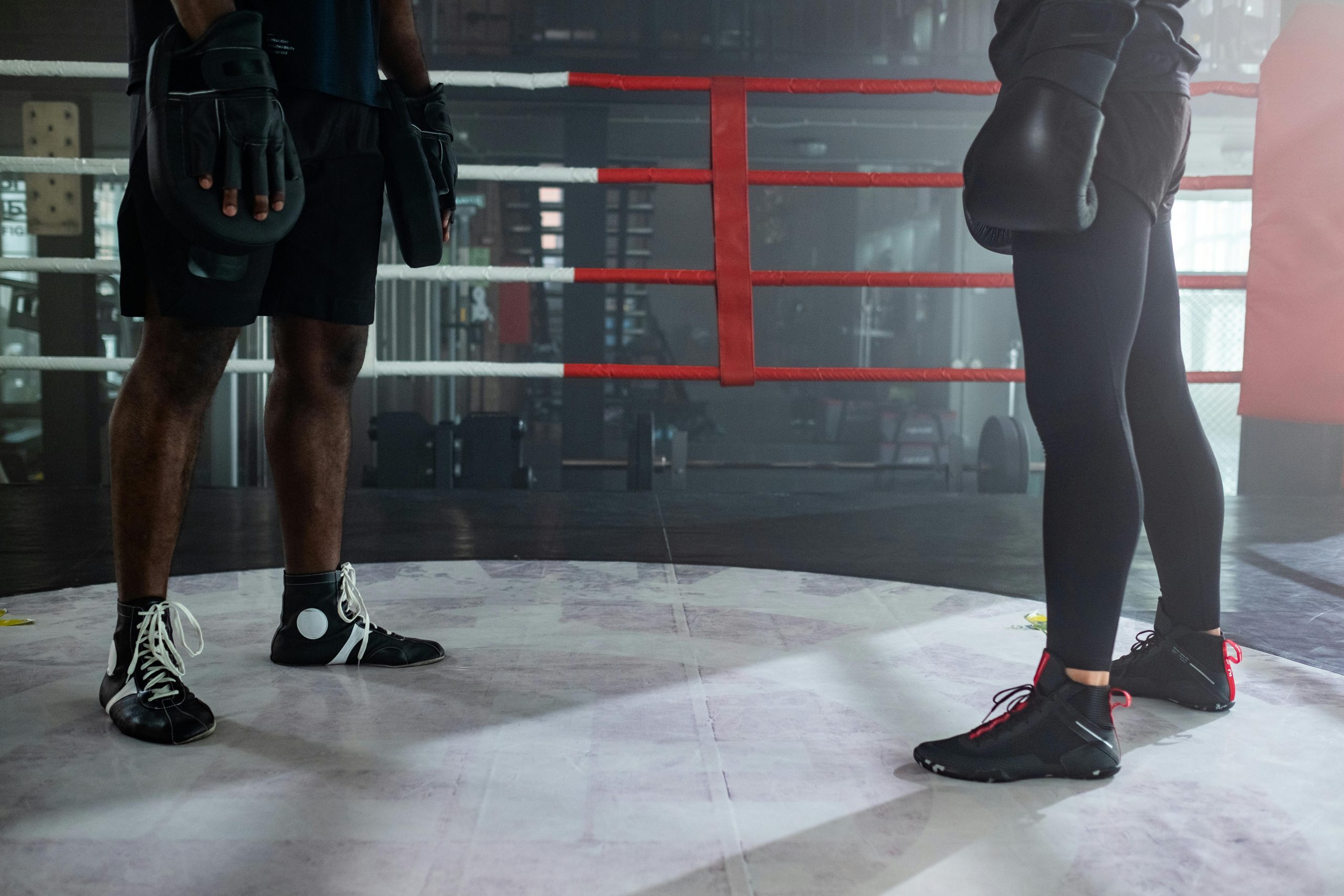 Close-up of two boxers training in a boxing ring with focus on their footwear and gear.